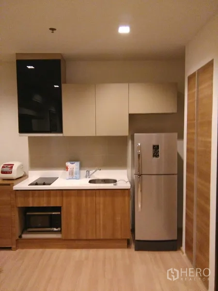 Condominium for rent or sale in Sathon, Bangkok - Modern kitchenette with cooktop, sink, microwave and stainless refrigerator.