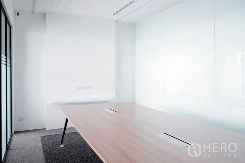 Office Space for rent in Khlong Toei, Bangkok - Compact meeting room with a large wooden table, whiteboard wall, and frosted glass partitions.