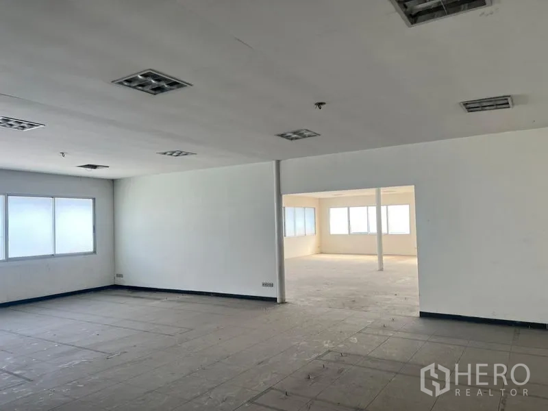 Warehouse for rent in Suan Luang, Bangkok - Two connected office rooms inside the building with a wide opening and support column.