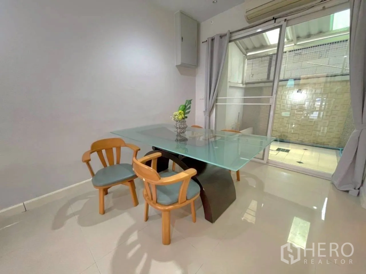 联排别墅 for rent in Bang Kho Laem, Bangkok - 餐区配玻璃餐桌和四把椅子，旁为通向后院的推拉门。