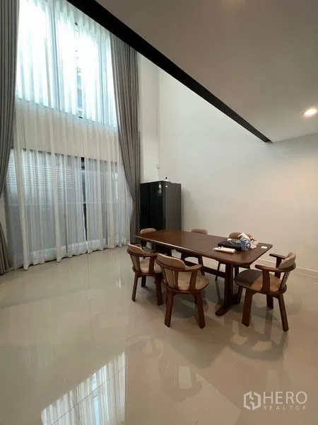 Townhouse for rent in Suan Luang, Bangkok - Open dining space with glossy tile flooring, tall drapes and a mezzanine void above.