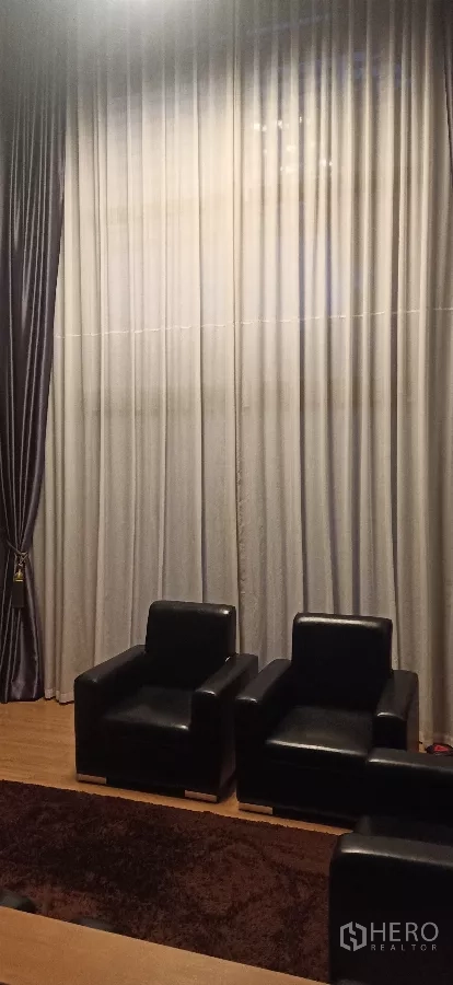 บ้าน ให้เช่าหรือขายในKhan Na Yao, Bangkok - มุมนั่งเล่นเพดานสูง ผ้าม่านโปร่งยาวจรดพื้น พร้อมเก้าอี้หนังสีดำสองตัว