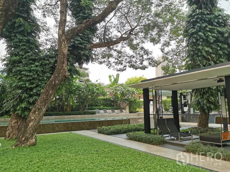 公寓 出租在Watthana, Bangkok - 花园凉亭、躺椅与大树，紧邻泳池。