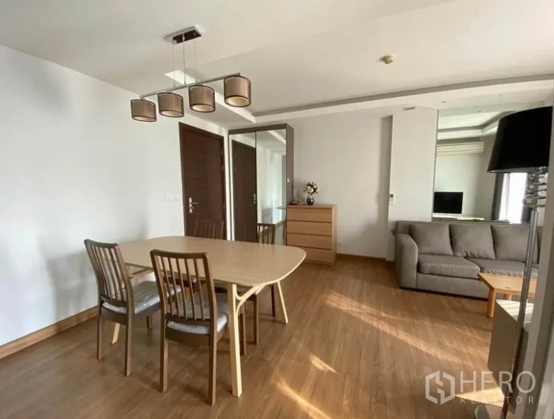 คอนโด ให้เช่าในHuai Khwang, Bangkok - โต๊ะทานอาหารข้างโซฟา ในห้องนั่งเล่นคอนโดสว่างพื้นไม้