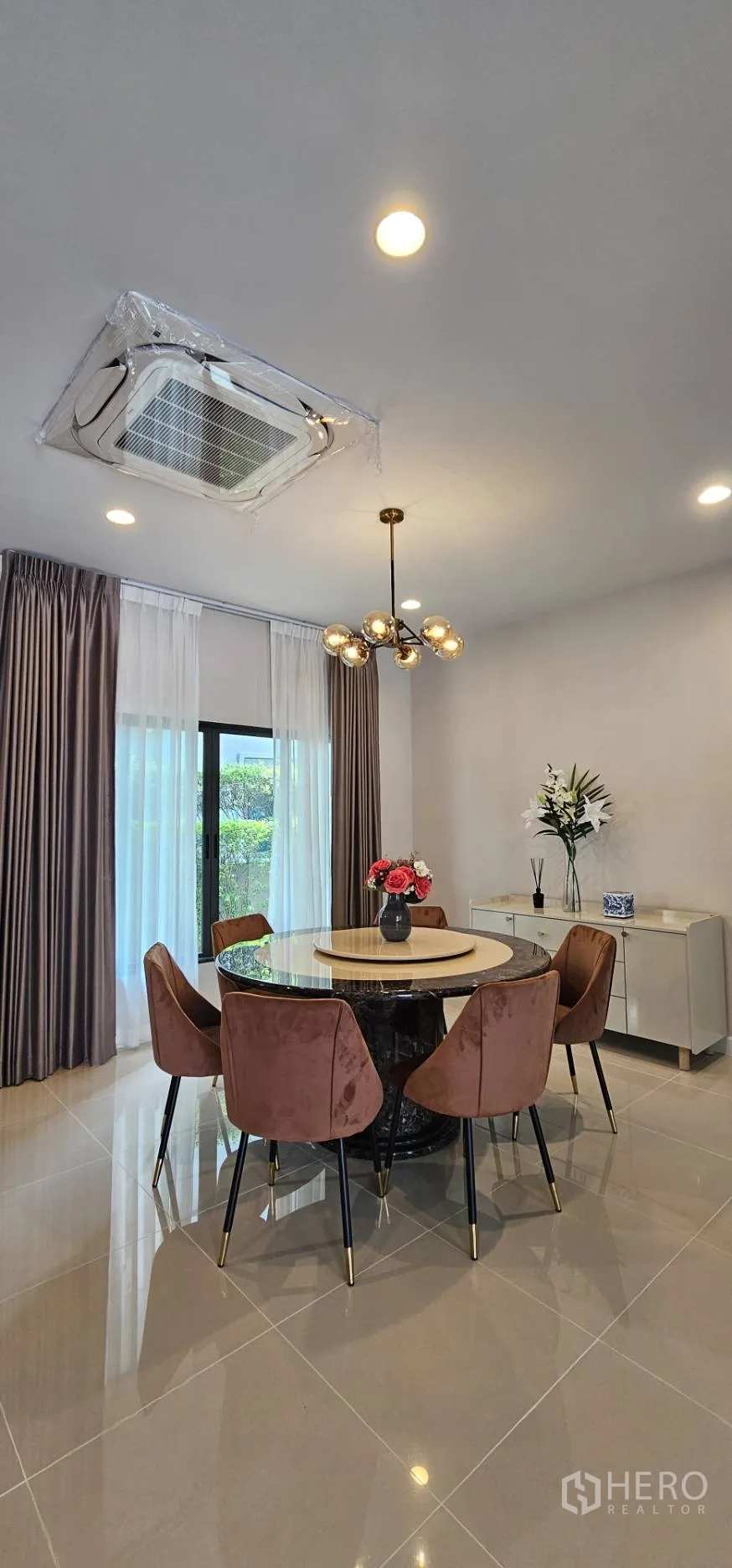Detached House for rent in Bang Kapi, Bangkok - Dining room with round marble table, statement chandelier and tall curtains.