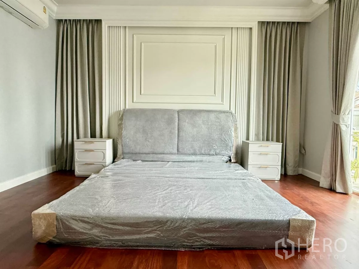 Townhouse for rent in Bang Kho Laem, Bangkok - Primary bedroom with upholstered headboard, twin nightstands, tall curtains and wood flooring