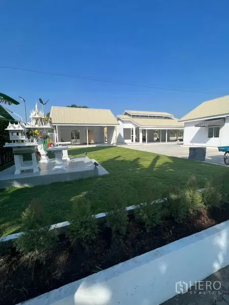 พื้นที่ขายปลีก ให้เช่าในPrawet, Bangkok - สนามหญ้าและภูมิทัศน์ระหว่างอาคารค้าปลีกสีขาวแบบโลว์ไรส์และลานกลางแจ้งสะอาด