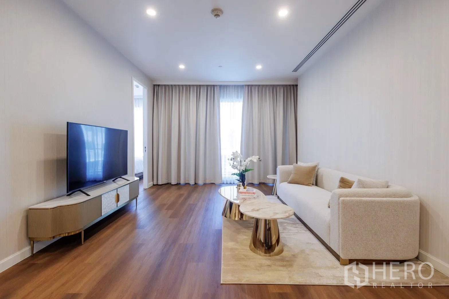 公寓 for rent or sale in Pathum Wan, Bangkok - 客厅配沙发、电视柜与落地窗帘。
