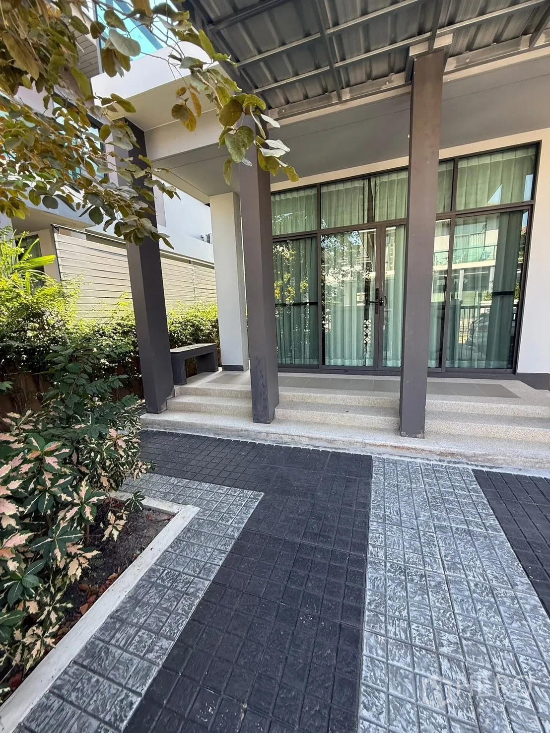 Detached House for rent in Prawet, Bangkok - Front entrance with sliding glass doors, covered terrace and landscaped plants.