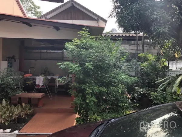 บ้าน ให้เช่าในKhlong Toei, Bangkok - เฉลียงมุงหลังคาปูพื้นกระเบื้องเทอราโคตา ข้างสวนร่มรื่นและลานจอดรถในบ้าน