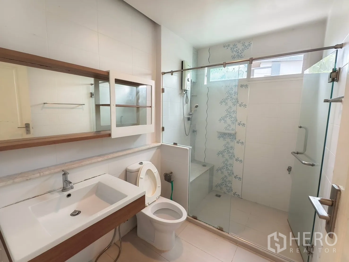 Detached House for rent in Bang Kapi, Bangkok - Bathroom with long mirror, vanity and sliding glass shower.