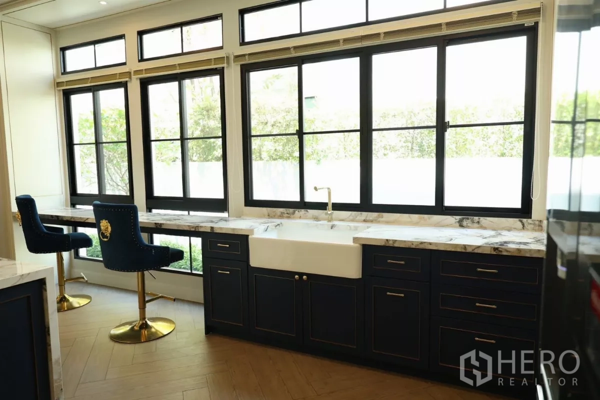 Detached House for rent or sale in Saphan Sung, Bangkok - Kitchen window counter with farmhouse sink, marble surfaces, and bar stools.
