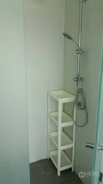 Condominium for rent in Watthana, Bangkok - Walk-in shower with handheld showerhead and a white corner storage shelf.