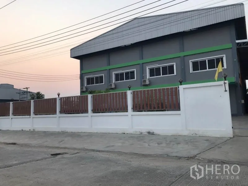 工厂 出售在Pak Kret, Nonthaburi - 灰色工厂外立面，白色围墙与金属大门
