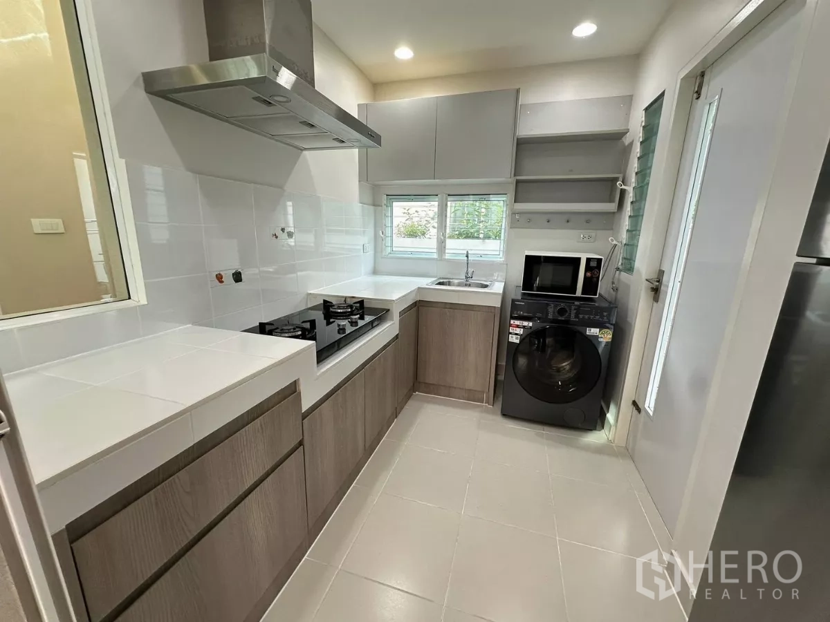 Detached House for rent in Bang Phli, Samut Prakan - Separate kitchen with gas hob, range hood, sink, and appliances including washer and microwave.