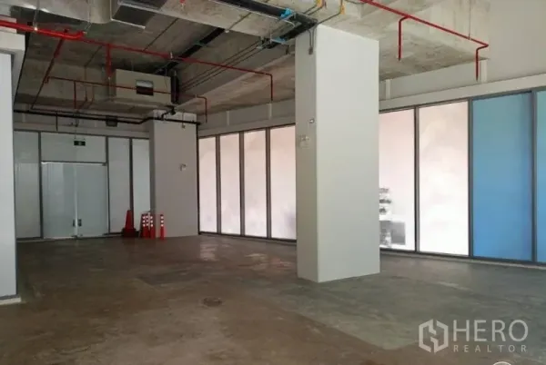 零售空间 出租在Watthana, Bangkok - 开敞店铺内部，承重柱、紧急出口门与周边通高窗