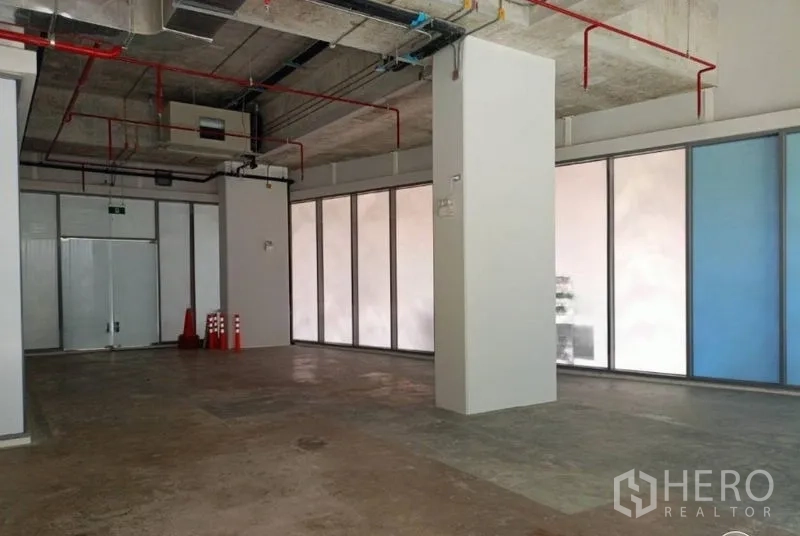 零售空间 出租在Watthana, Bangkok - 开敞店铺内部，承重柱、紧急出口门与周边通高窗