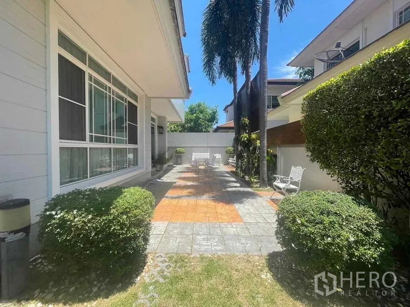 บ้าน ขายในSamut Prakan - ลานพักผ่อนปูพื้นกระเบื้อง พร้อมเก้าอี้กลางแจ้ง ต้นปาล์ม และแนวรั้วพุ่มไม้