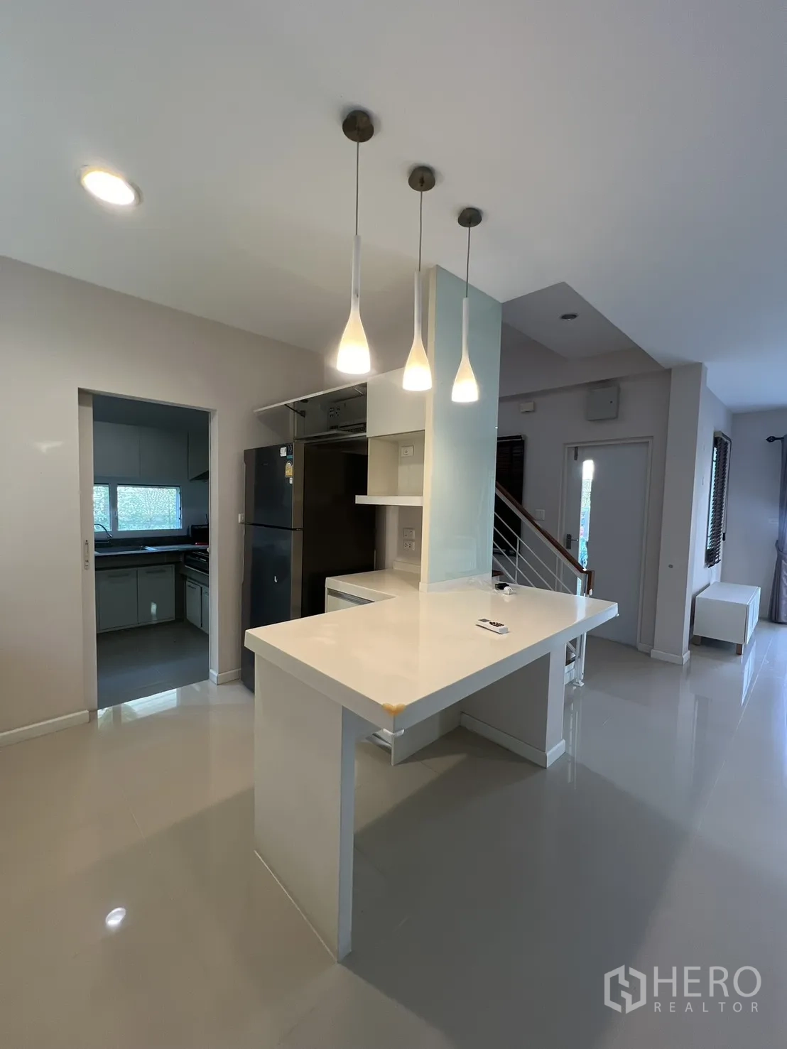 บ้านเดี่ยว for rent in Bang Kapi, Bangkok - ไอส์แลนด์ครัวสว่างพร้อมโคมไฟแขวน ใกล้บันไดและประตูทางเข้า.