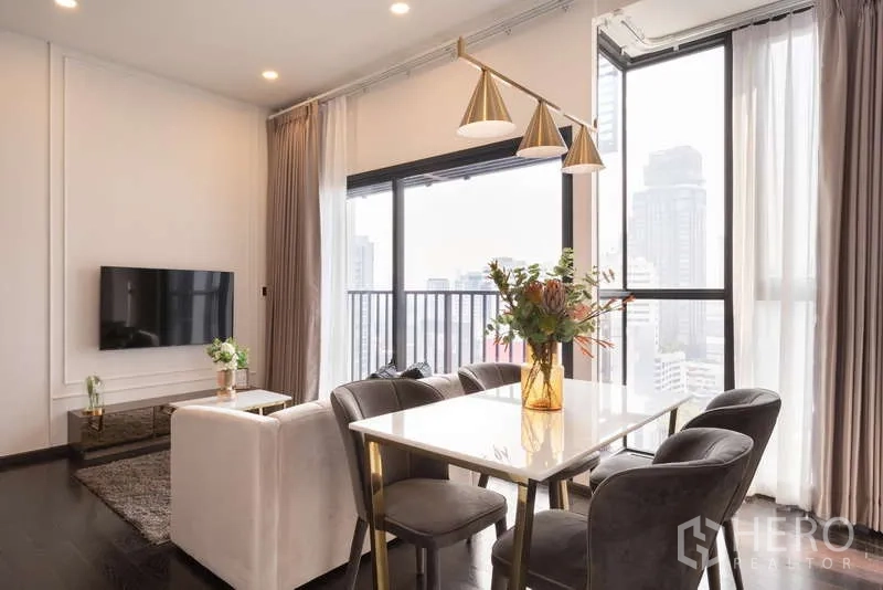 公寓 出租在Watthana, Bangkok - 餐区配大理石台面餐桌与金色吊灯，落地窗眺望天际线