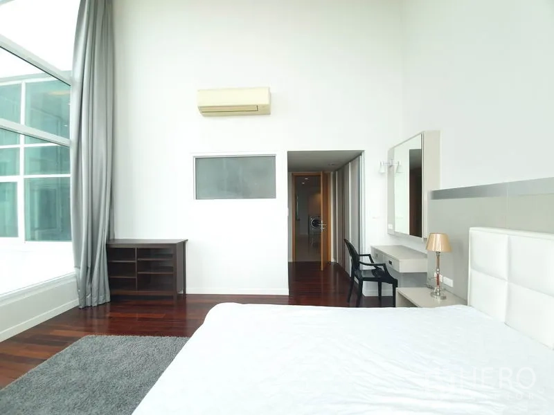 คอนโด ให้เช่าในRatchathewi, Bangkok - ห้องนอนสว่างเพดานสูง หน้าต่างบานใหญ่ เตียงหัวเตียงสีขาว และพื้นไม้เงางาม.