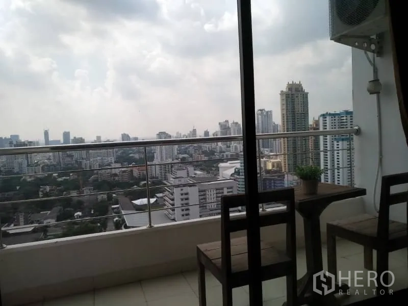 Condominium for rent in Watthana, Bangkok - High-floor balcony with table set overlooking the Bangkok skyline.