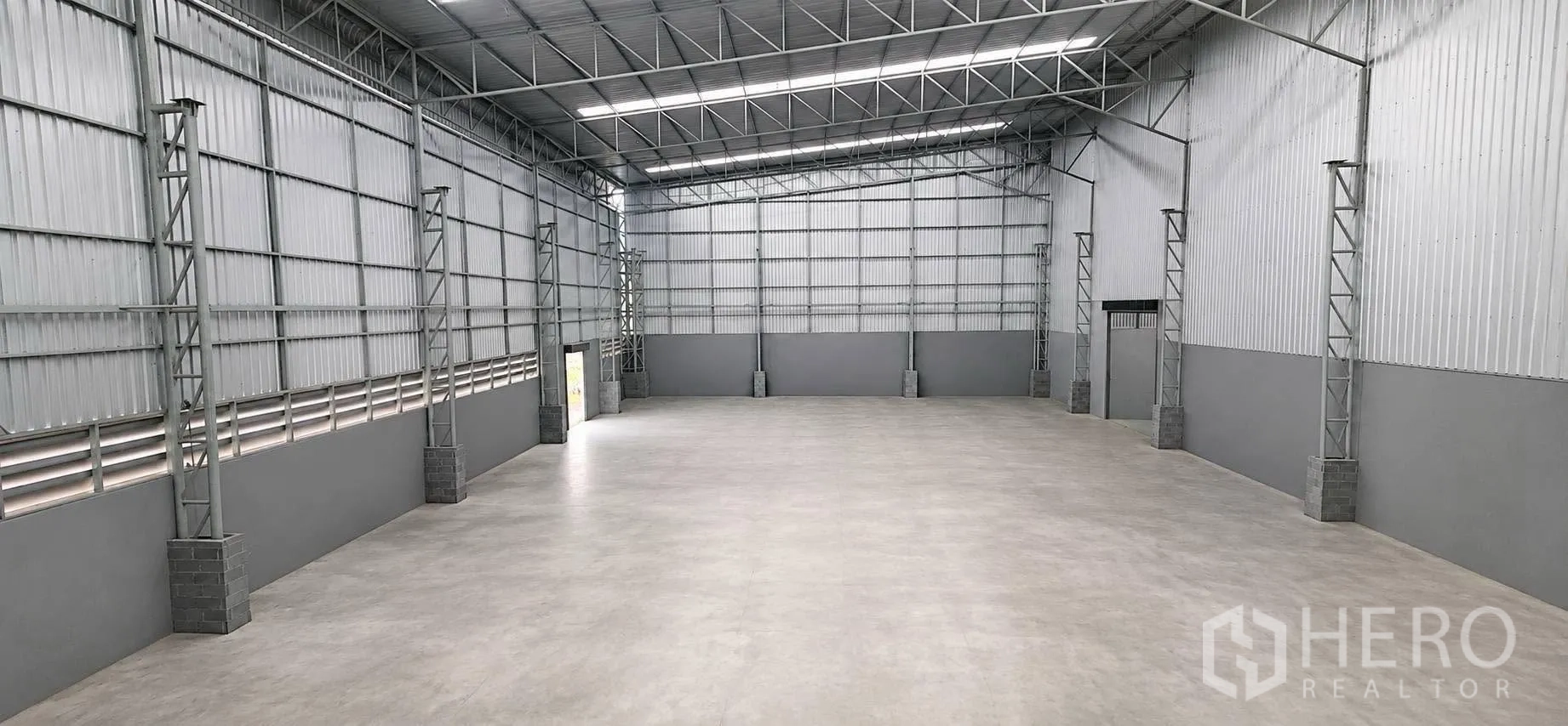 Warehouse for rent in Bang Khun Thian, Bangkok - Warehouse interior with high steel truss roof, smooth concrete floor, and large entry doors.
