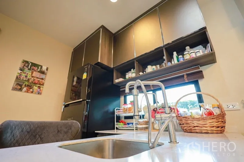 Detached House for rent or sale in Lam Luk Ka, Pathum Thani - Modern kitchen with high cabinets, black fridge and stainless sink.