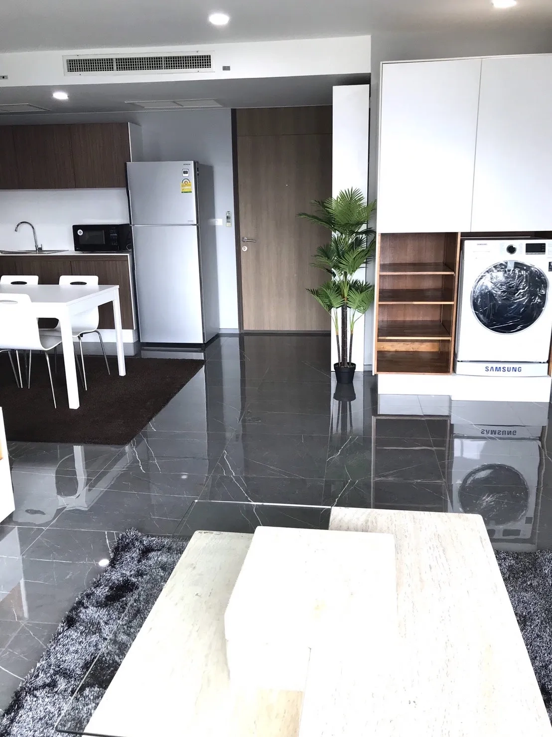 公寓 出租在Khlong Toei, Bangkok - 入口与厨房区，亮面地砖与内嵌洗烘机位。