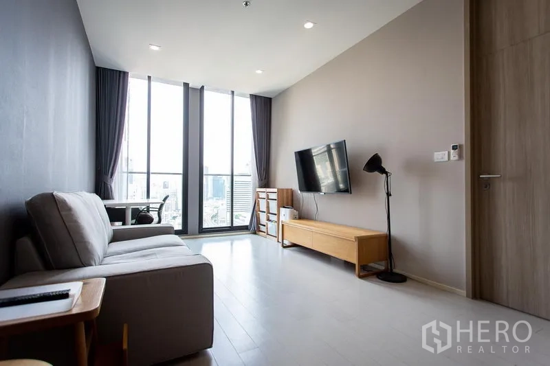Condominium for rent in Pathum Wan, Bangkok - Bright living room with floor-to-ceiling windows, city view, sofa and wall-mounted TV in Pathum Wan, Bangkok