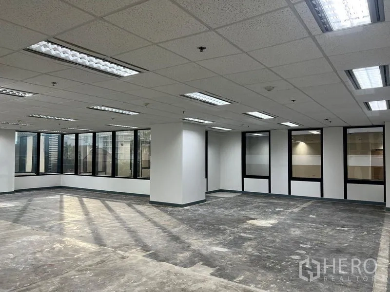 Office Space for rent in Khlong Toei, Bangkok - Open workspace with fluorescent lighting, multiple glass windows and clean white columns in Khlong Toei, Bangkok.
