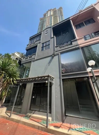 店屋 出租在Watthana, Bangkok - 素坤逸多层商铺外观，临街大玻璃立面，背景有高楼。