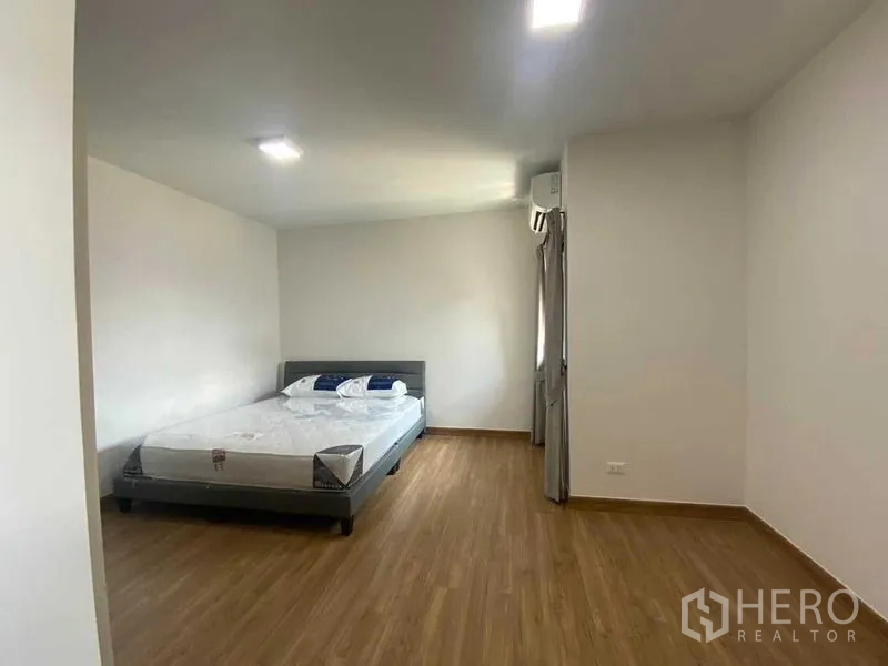 独立式住宅 出租在Khan Na Yao, Bangkok - 极简卧室，双人床、木地板与空调。