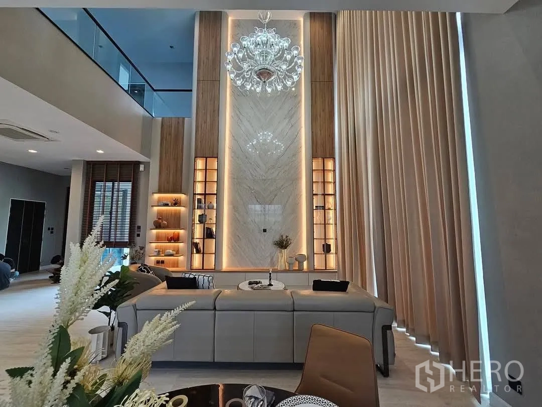 Detached House for rent or sale in Suan Luang, Bangkok - Living and dining room with marble feature wall and tall curtains.