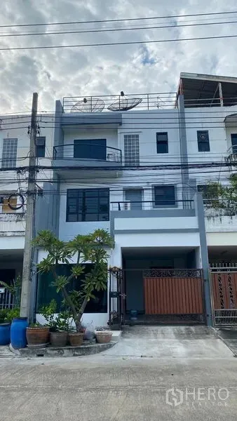 联排别墅 出租在Bang Na, Bangkok - 曼谷邦纳三层联排别墅外观，带有门禁车位与盆栽。