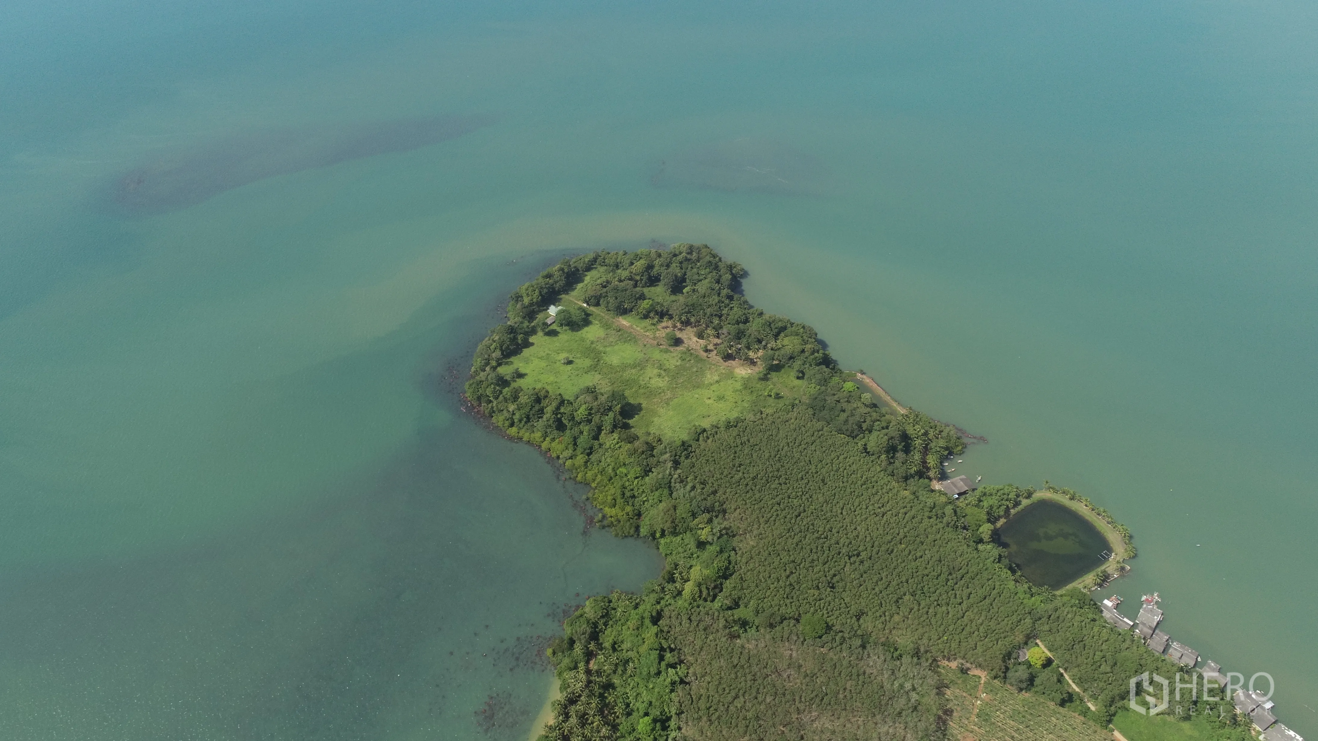 Land for sale in Khlong Toei, Bangkok - Wide aerial panorama showing a private headland with open meadows and forest edges extending into the sea.