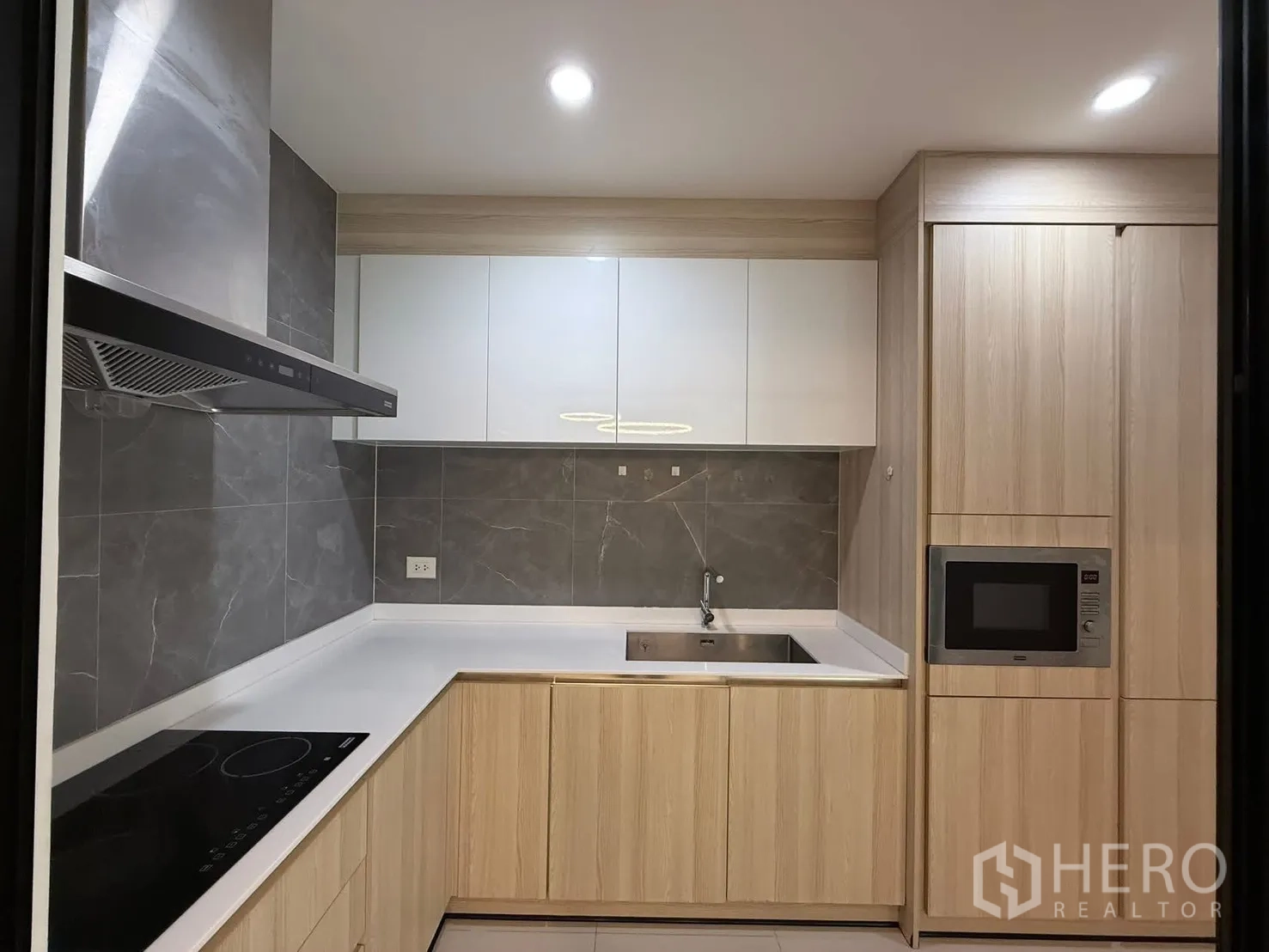 Townhouse for rent in Saphan Sung, Bangkok - Enclosed U-shaped kitchen with induction hob, hood, sink and microwave.