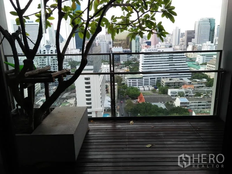 Condominium for rent in Sathon, Bangkok - Private balcony with wooden deck and glass railing overlooking the Bangkok skyline near Lumphini.