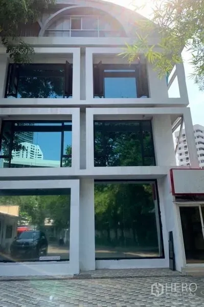 独立商业地产 出租在Khlong Toei, Bangkok - 多层独栋建筑网格立面与深色玻璃，临近BTS Phrom Phong站。