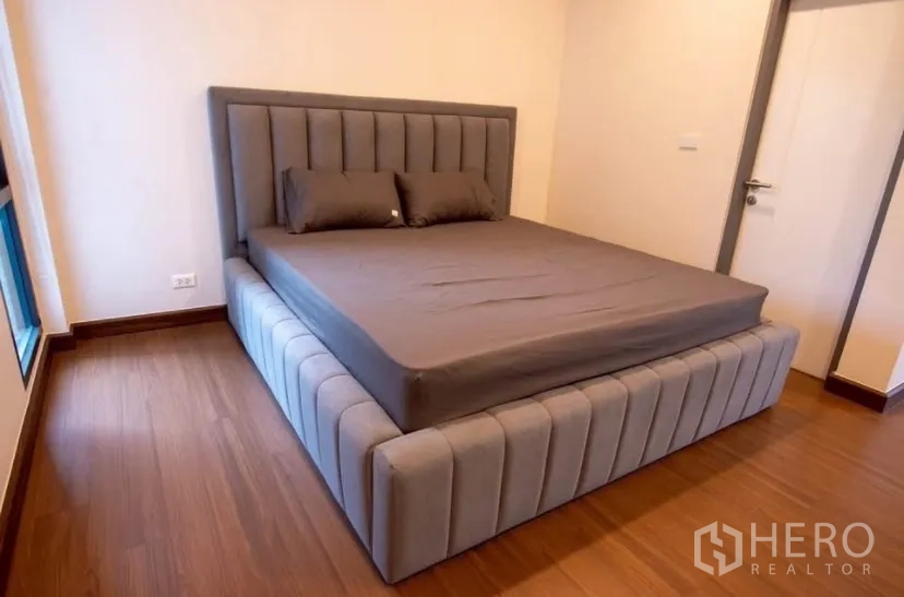 Detached House for rent in Bang Phli, Samut Prakan - Guest bedroom with gray upholstered bed and wooden flooring.