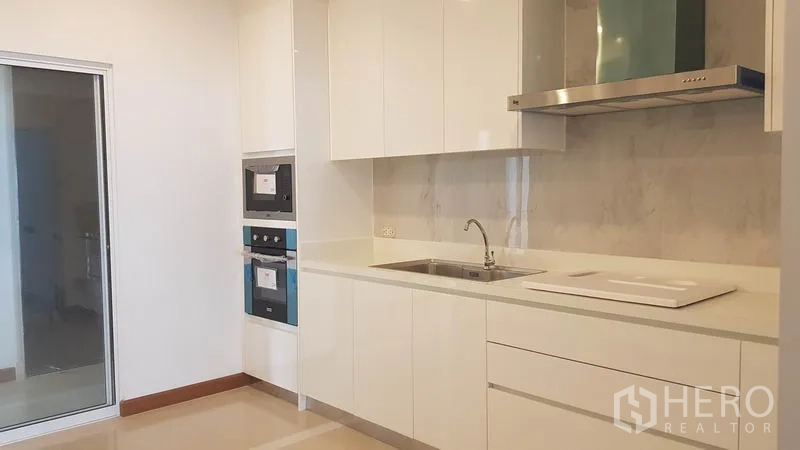 Condominium for rent or sale in Yan Nawa, Bangkok - Bright modern kitchen with white cabinets, built-in oven and range hood.