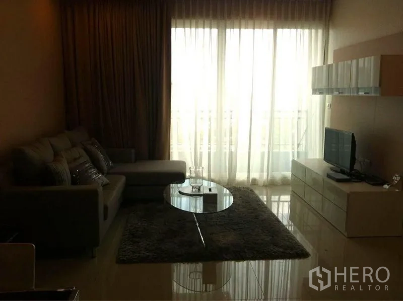 公寓 出售在Ratchathewi, Bangkok - 采光良好的客厅，电视柜与玻璃茶几，纱帘后为阳台门。