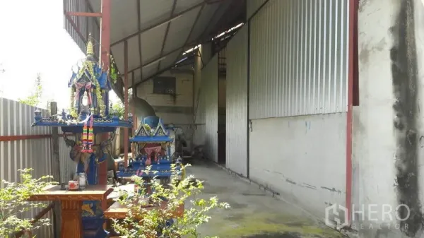 货栈 出售在Pathum Thani - 外侧走道，波纹金属墙与雨棚覆盖，入口旁的室外作业区。