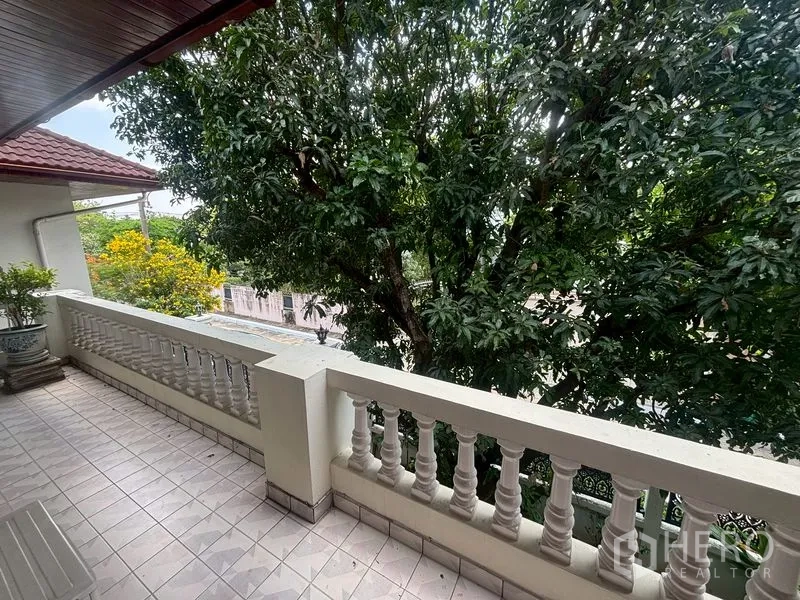 独栋房屋 for sale in Suan Luang, Bangkok - 铺砖阳台配白色栏杆，绿树成荫的景观。