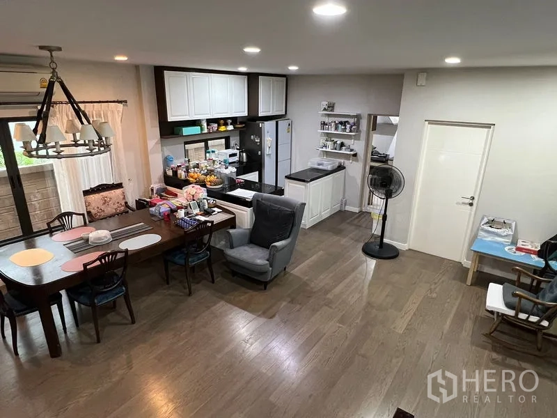 Detached House for sale in Bang Kapi, Bangkok - Open-plan kitchen and dining area with white cabinetry, island counter and hardwood floors.