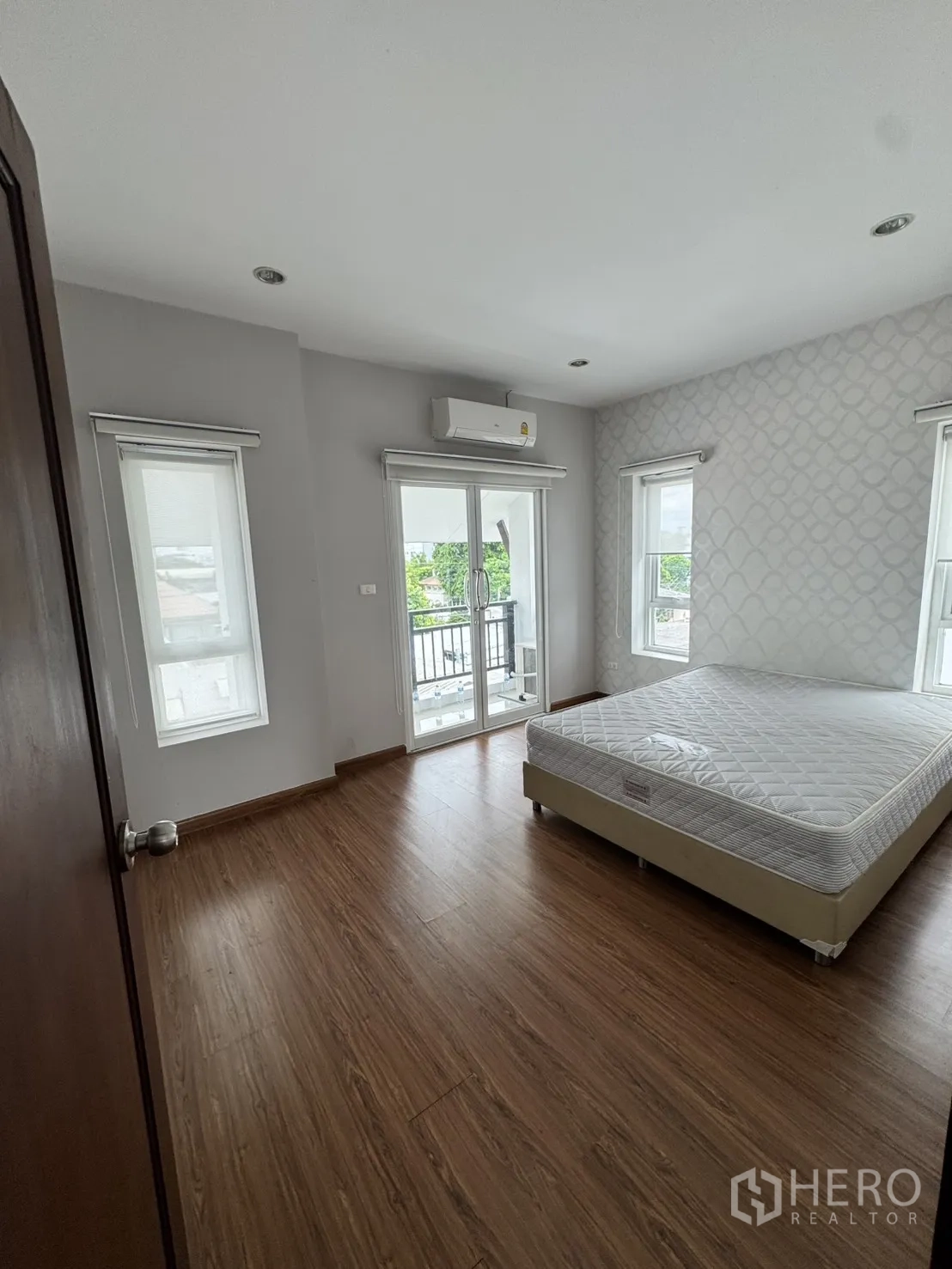 Home Office for rent in Watthana, Bangkok - Bedroom with wood-look flooring, balcony doors, and air-conditioning.