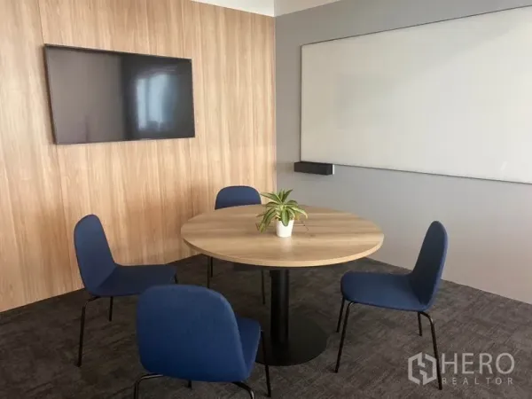 办公空间 出租在Pathum Wan, Bangkok - 小型会议室，圆桌配四把蓝色椅子，墙面电视与白板。