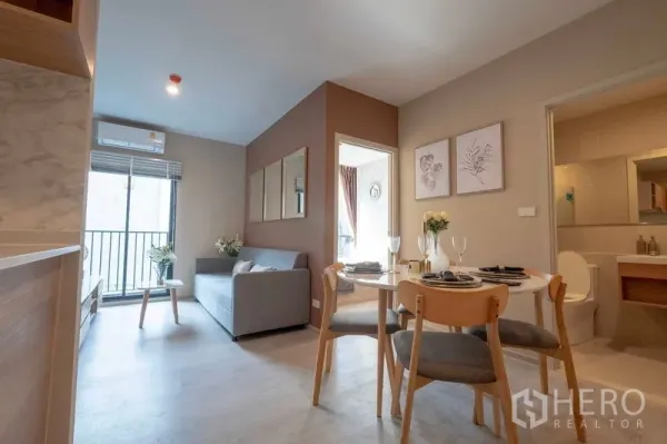 公寓 出租在Bang Na, Bangkok - 开放式客餐厅带阳台、沙发与浴室入口。