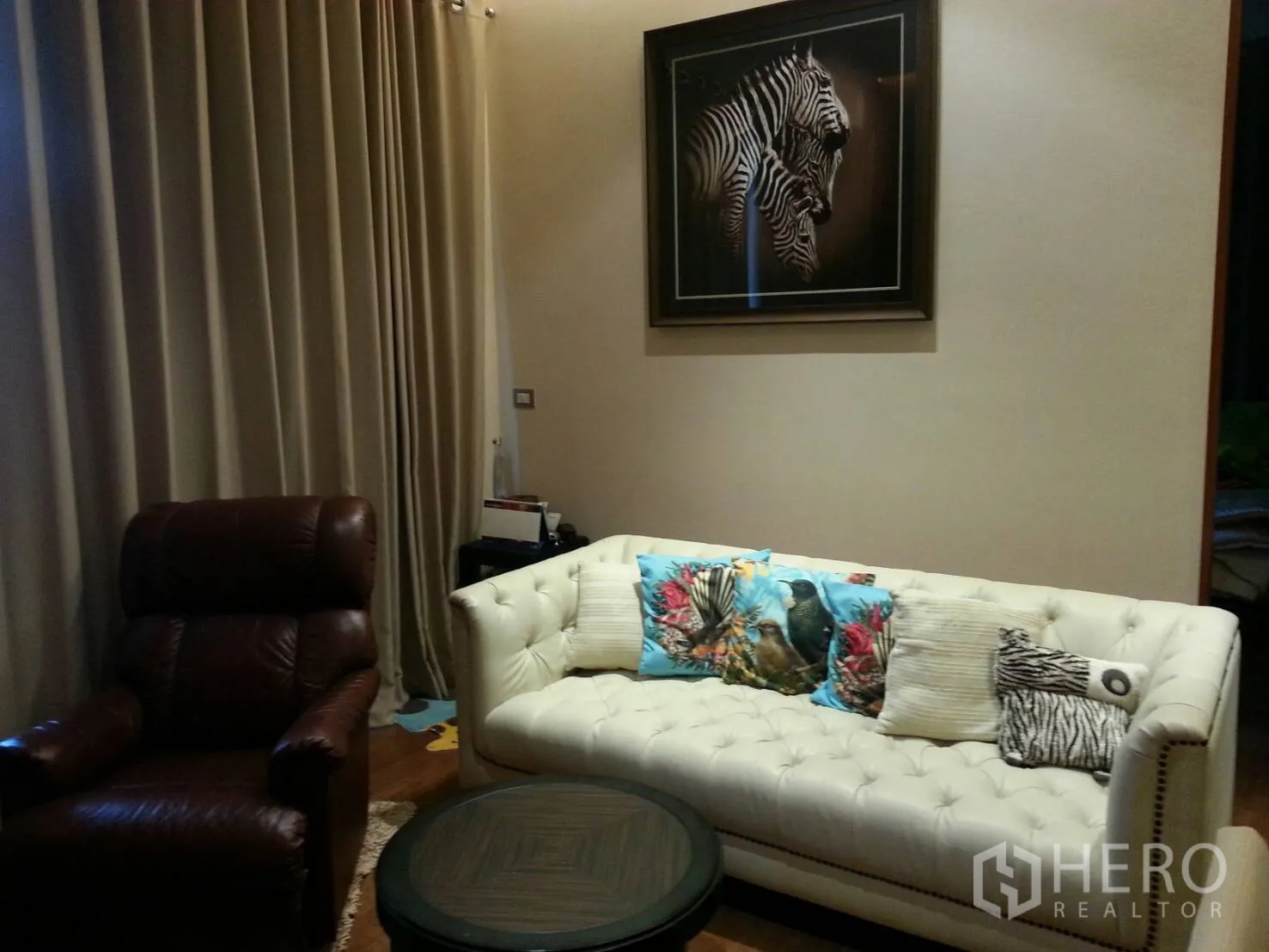 คอนโด ให้เช่าหรือขายในKhlong Toei, Bangkok - ห้องนั่งเล่นอบอุ่น โซฟาหนังบุทัฟสีขาว เก้าอี้เอน โต๊ะกลางรูปทรงกลม ภาพม้าลาย และผ้าม่านเต็มผนัง