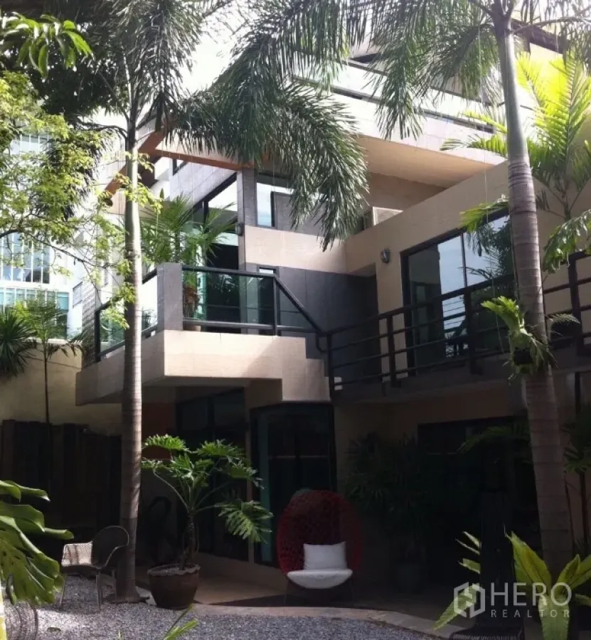 Detached House for rent in Wang Thonglang, Bangkok - Contemporary house exterior with balconies, large windows and a palm-lined courtyard.